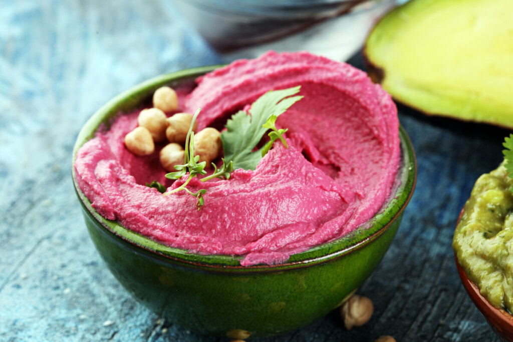 Homus rosa em um recipiente verde com grão-de-bico
