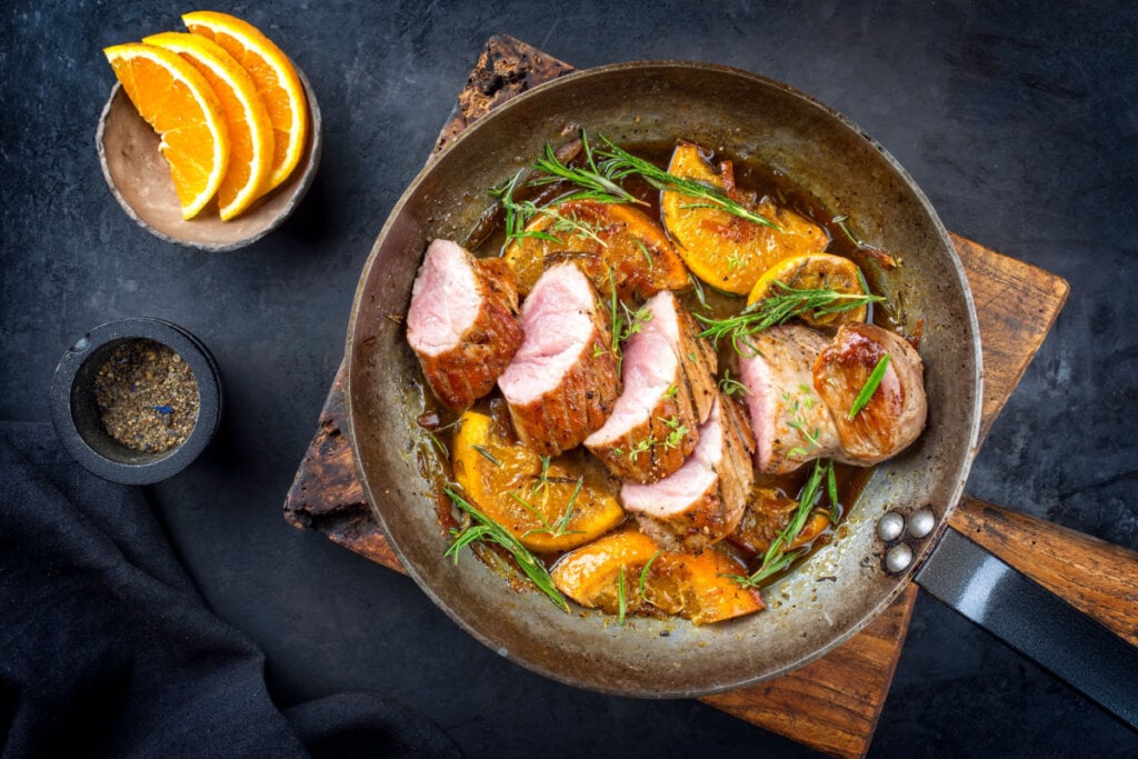 Carne assada em panela com molho, alecrim e fatias de laranja