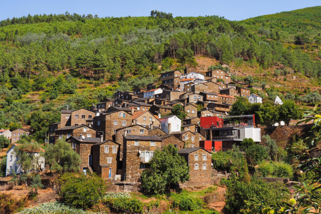 Vista de Piódão em Portugal, com casas em morro e árvores 