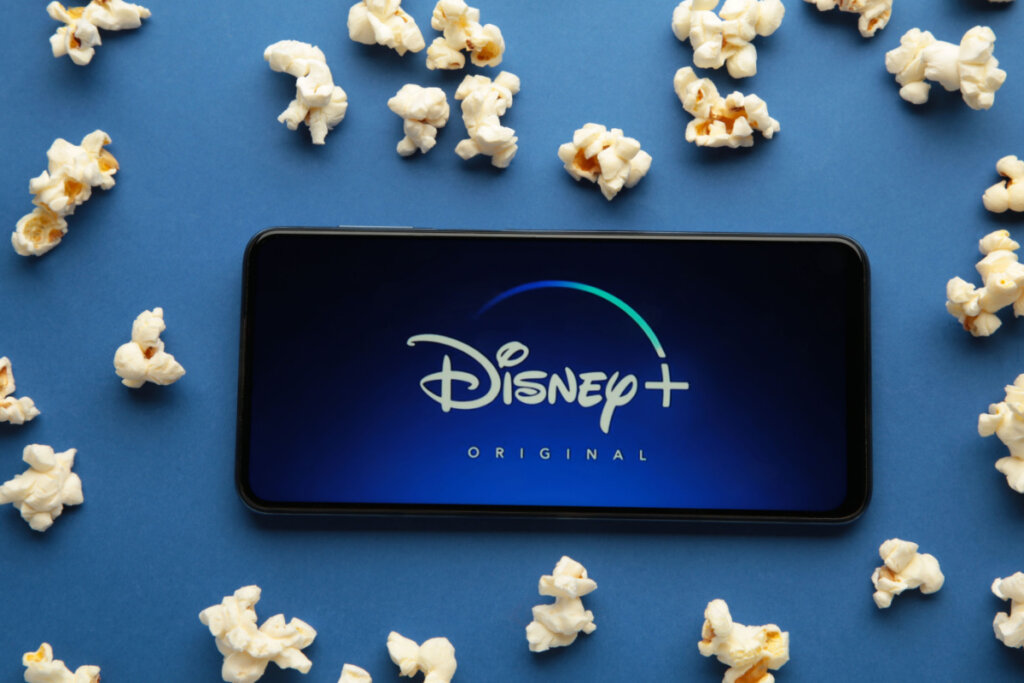 Smartphone com abertura do Disney+ ao redor de pipocas