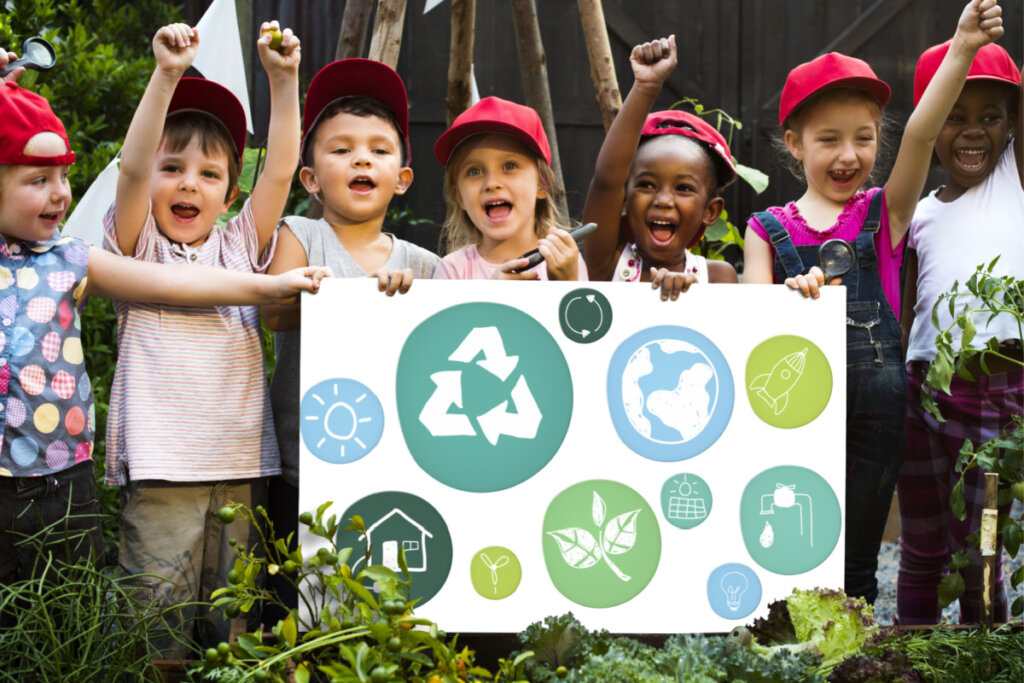 Crianças segurando um cartaz com várias imagens representando a importância de cuidar do meio ambiente