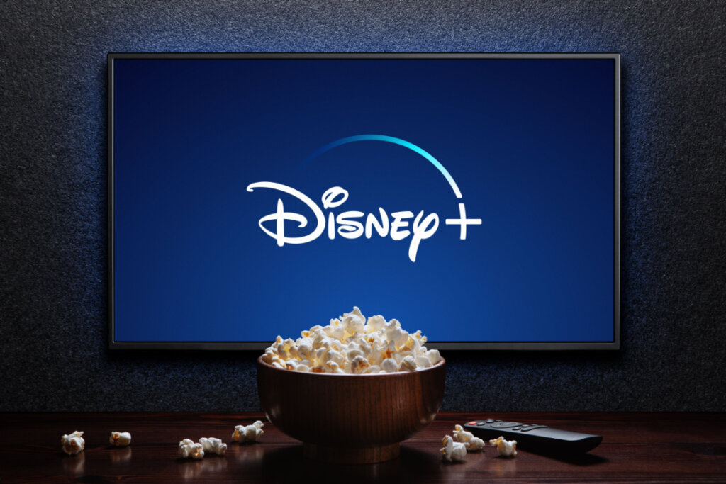 Smart TV com logo da Disney+, com balde de pipoca e controle remoto na frente