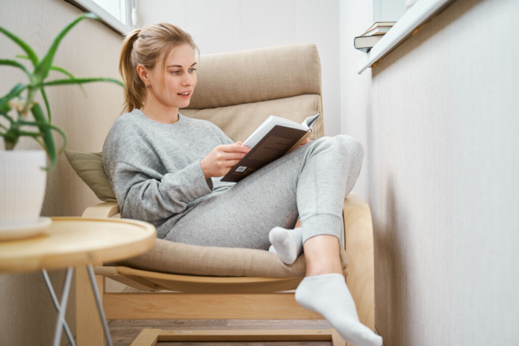 Mulher sentada em poltrona lendo livro