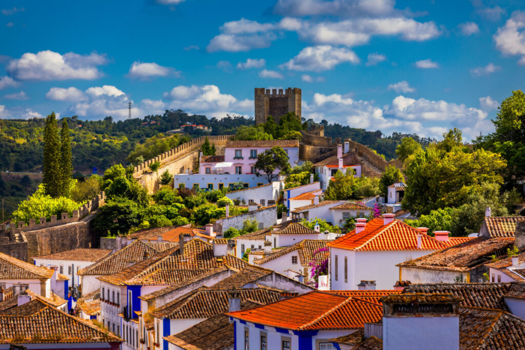 Vista de Óbidos em Portugal, com casas, castelo e árvores 