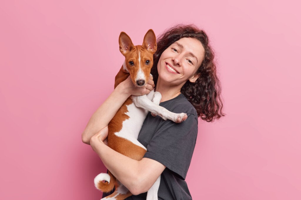 Mulher sorrindo e abraçada com cão