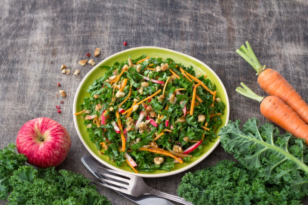 Salada de couve com cenoura em pote com cenoura, couve e maçã ao redor do recipiente