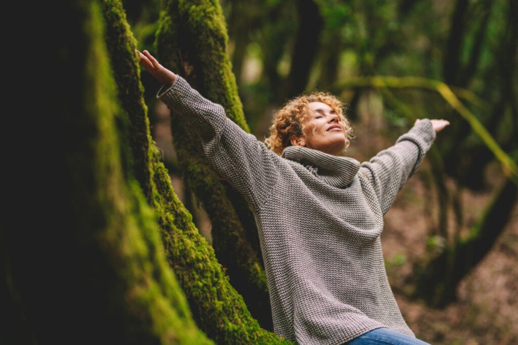 Mulher de braços abertos em natureza