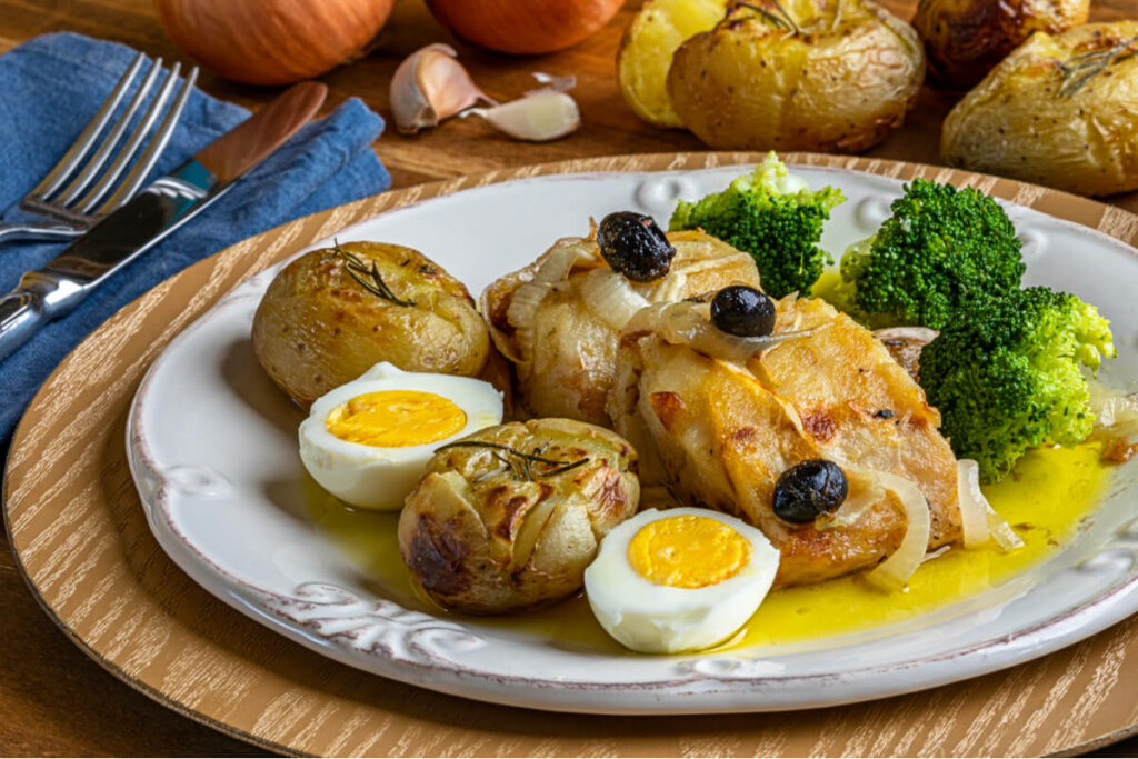 Bacalhau com batatas ao murro, ovo cozido, brócolis e azeitonas no prato branco