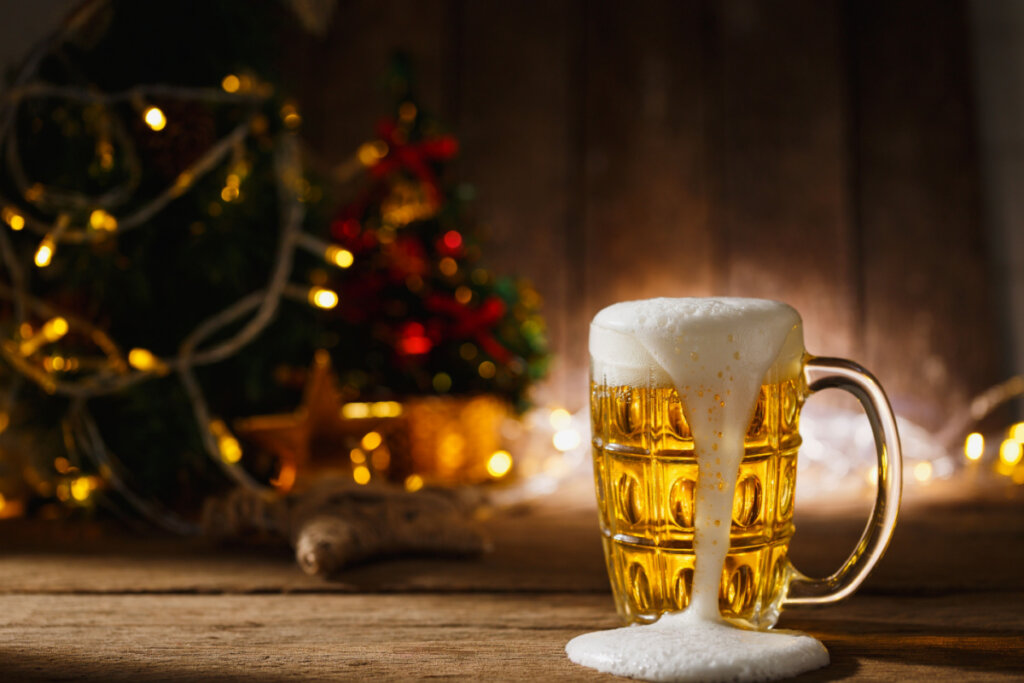 Cerveja em caneca na mesa de madeira com fundo de iluminação de Natal
