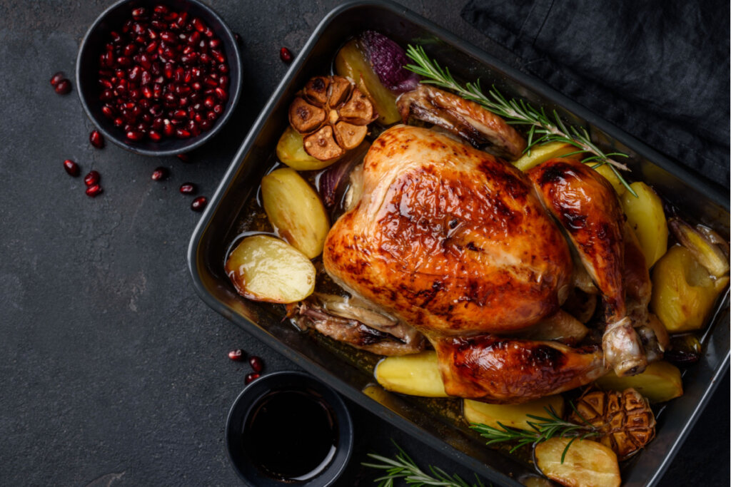 Frango assado ao molho de romã com batatas em uma assadeira preta