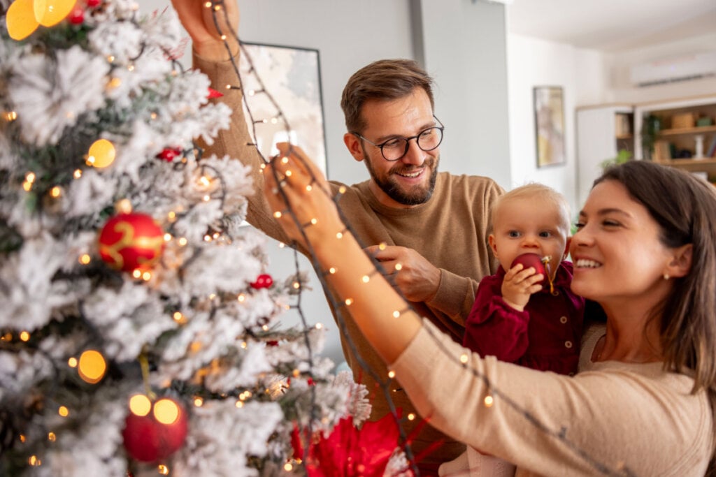 Família reunida decorando árvore de natal com pisca-pisca