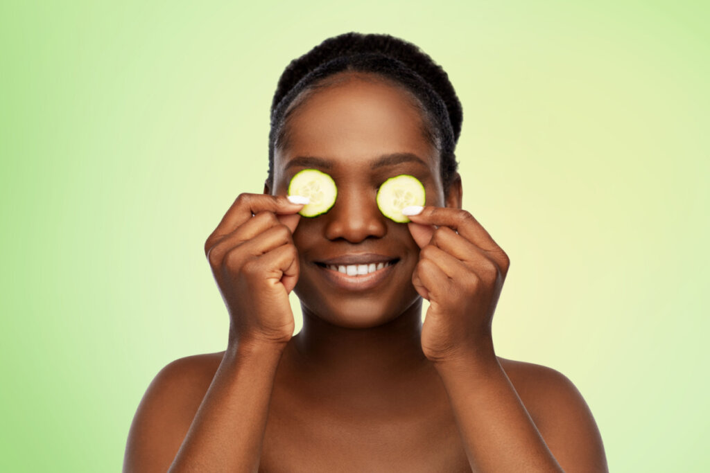Mulher fazendo máscara de olho de pepino sobre fundo natural verde limão