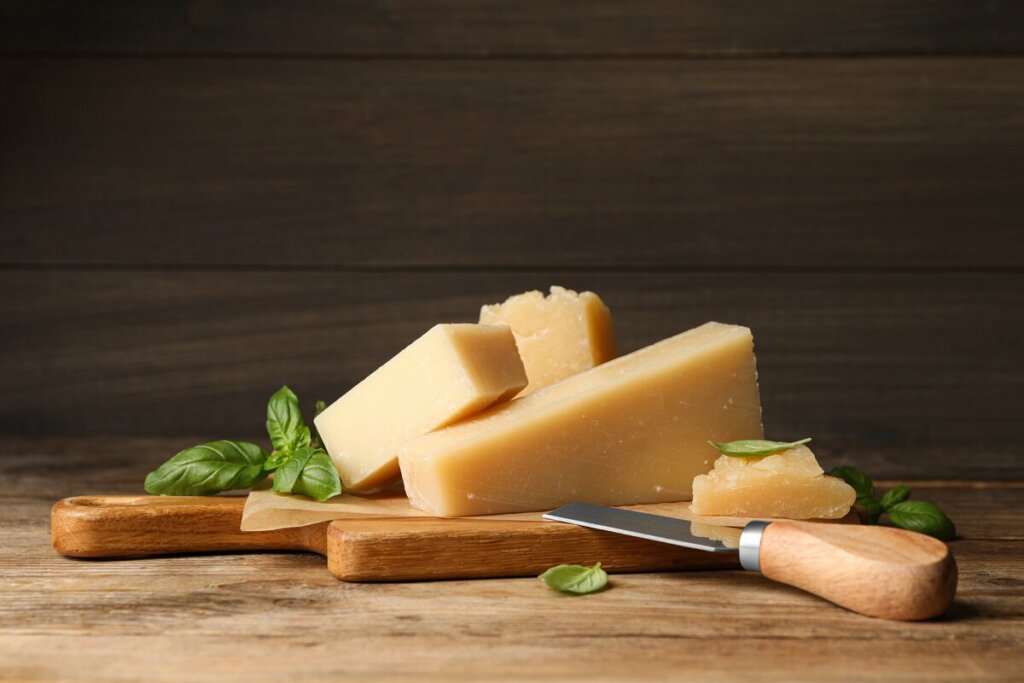 Pedaço de queijo em cima de uma tábua de madeira com uma faca