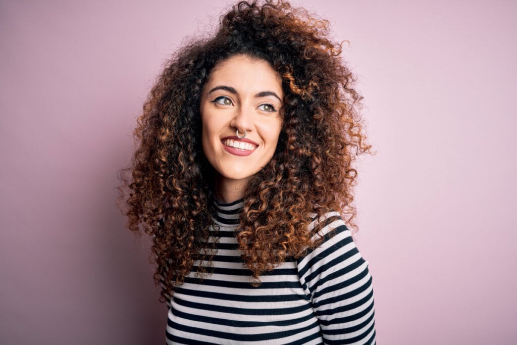 Mulher com cabelo cacheado sorrindo e de camiseta listrada