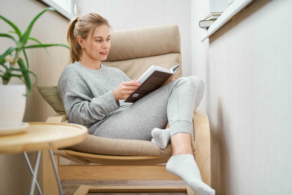 Mulher lendo livro na poltrona de casa