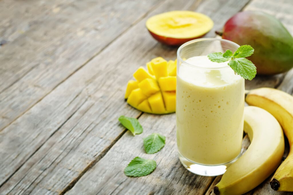 Smoothie de banana e manga em suporte de madeira