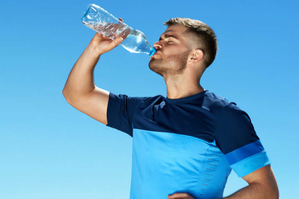 Homem bebendo água em uma garrafa reciclável