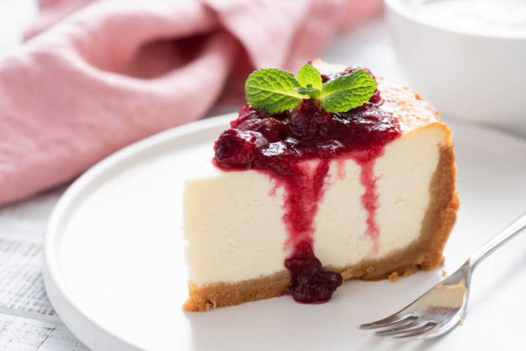 Fatia de cheesecake com geleia de frutas vermelhas em prato branco