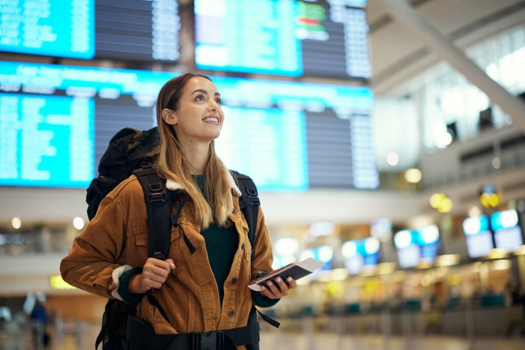 Mulher com mochila e passaporte nas mãos em um aeroporto 