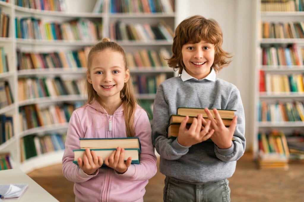 Menina e menino sorrindo segurando livros