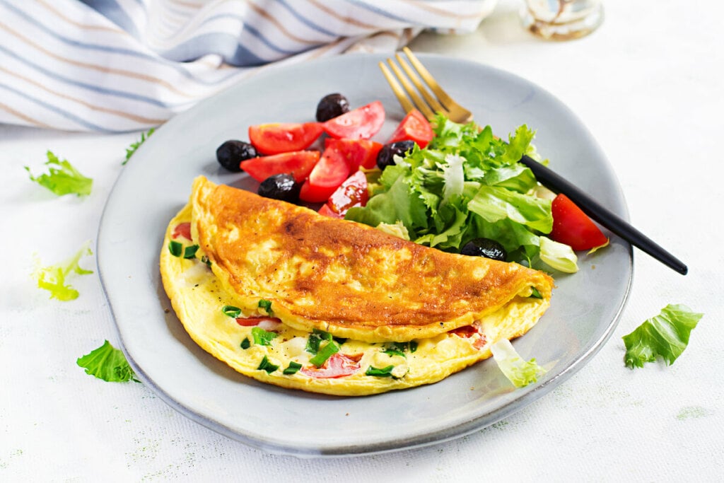 Omelete em cima de um prato branco com salda