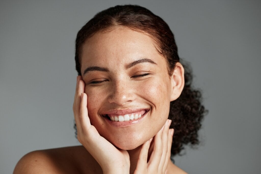 Mulher sorrindo com as mãos no rosto