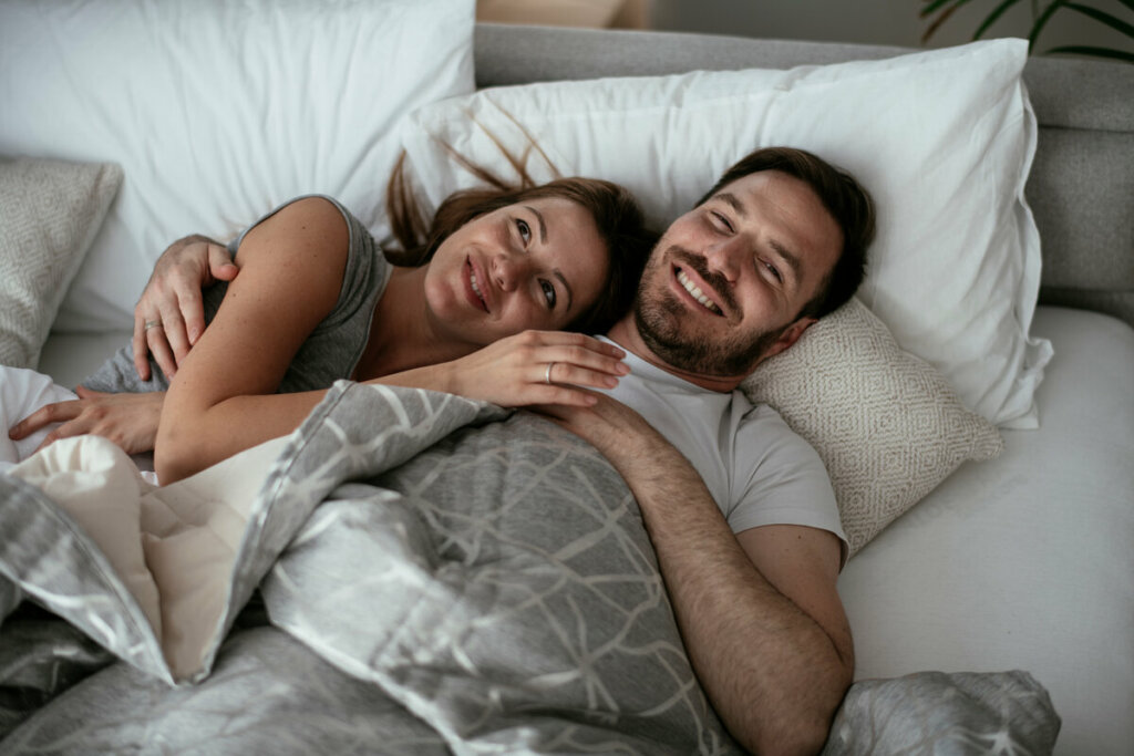 Mulher e homem sorrindo deitados em uma cama