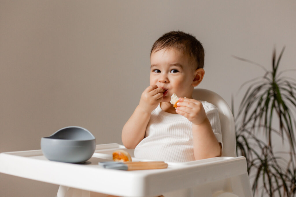 Bebê comendo algo na cadeirinha de bebê