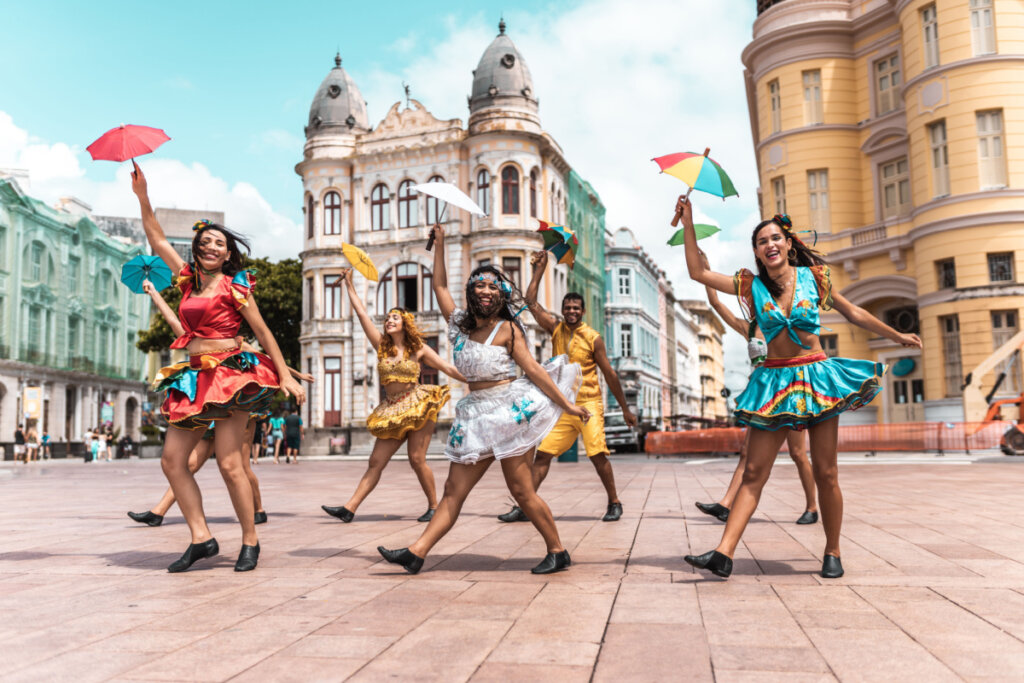 Pessoas dançando frevo na rua com roupas coloridas