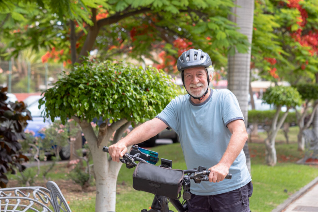 Homem idoso com capacete segurando bicicleta