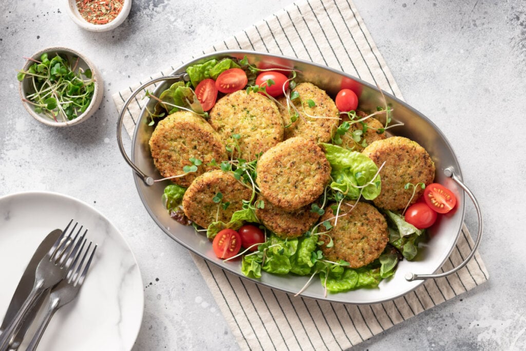 Hambúrgueres em meio à salada em um recipiente de metal