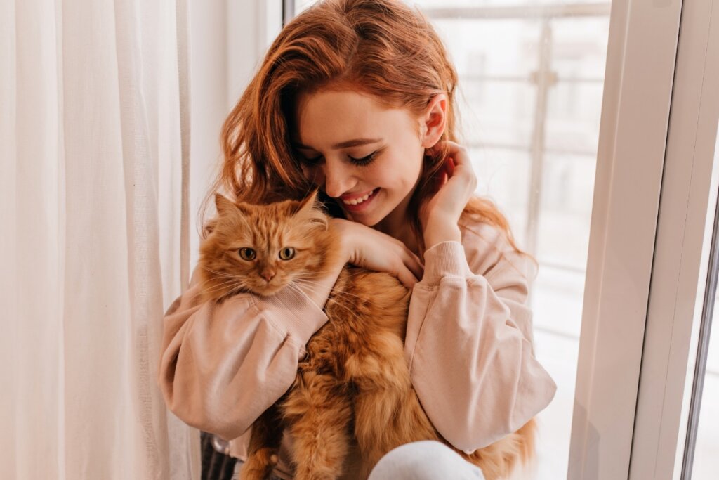 Mulher abraçando um gato laranja 