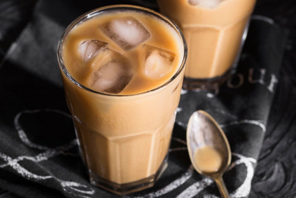 Café com leite e pedras de gelo em um copo 