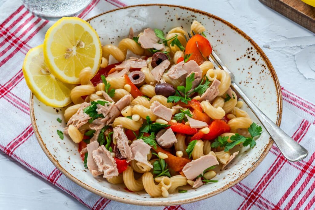 Recipiente branco com macarrão, atuam e azeitona preta