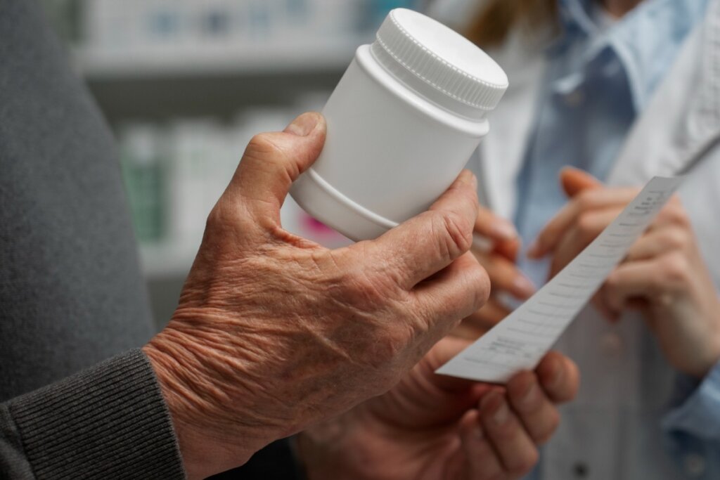 Mãos masculina segurando uma caixa de remédio e um papel