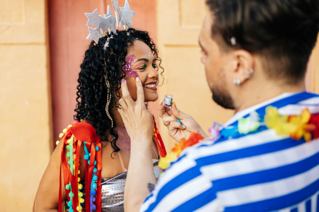 homem passando glitter no rosto de uma moça pronta para curtir o carnaval