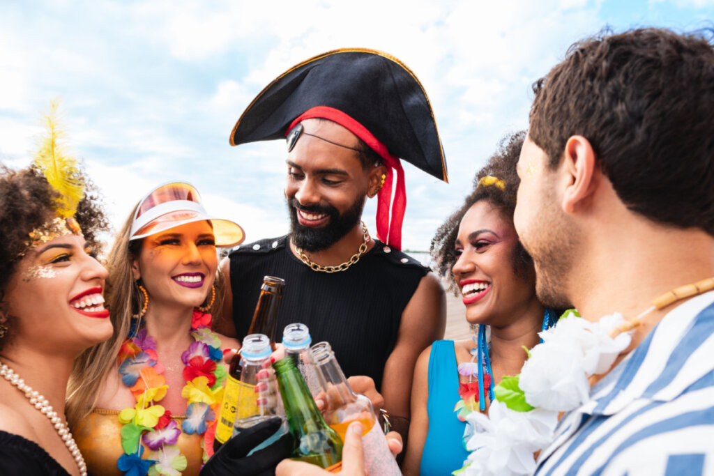 Pessoas com fantasia de Carnaval brindando com garrafa de cerveja