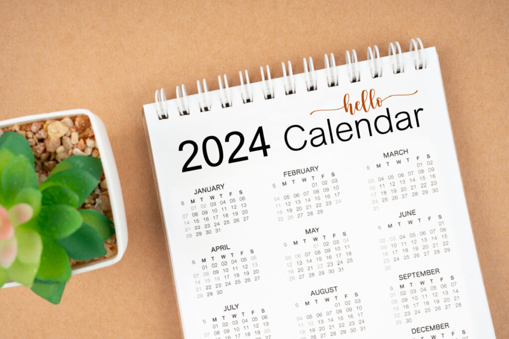 Calendário de 2024 em superfície marrom ao lado de planta