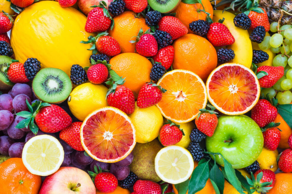 Diversas frutas juntas, como morangos, laranjas, kiwis, uvas e amoras.