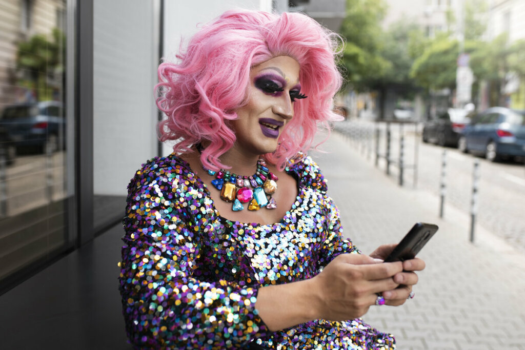 Drag queen mexendo em um celular na rua 