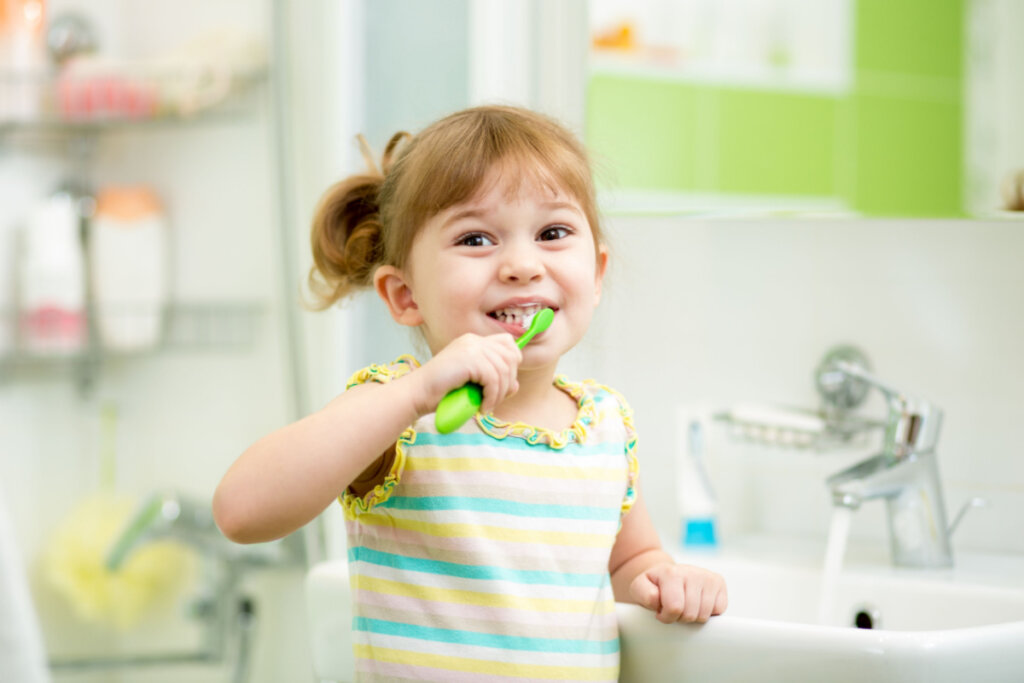Menina pequena escovando os dentes no banheiro