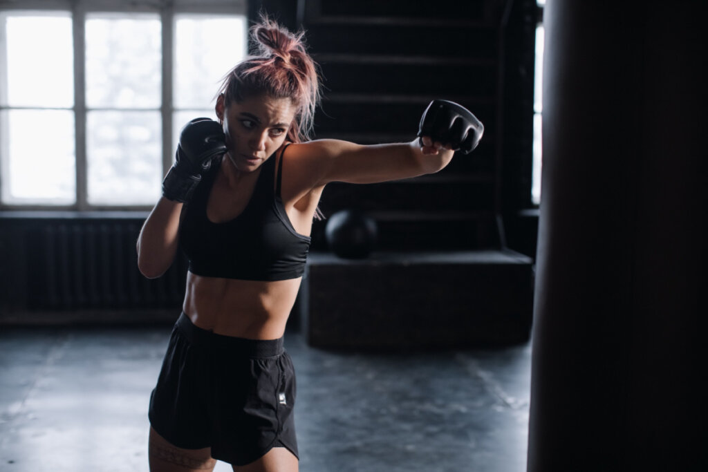 Mulher vestida de preto praticando boxe na academia