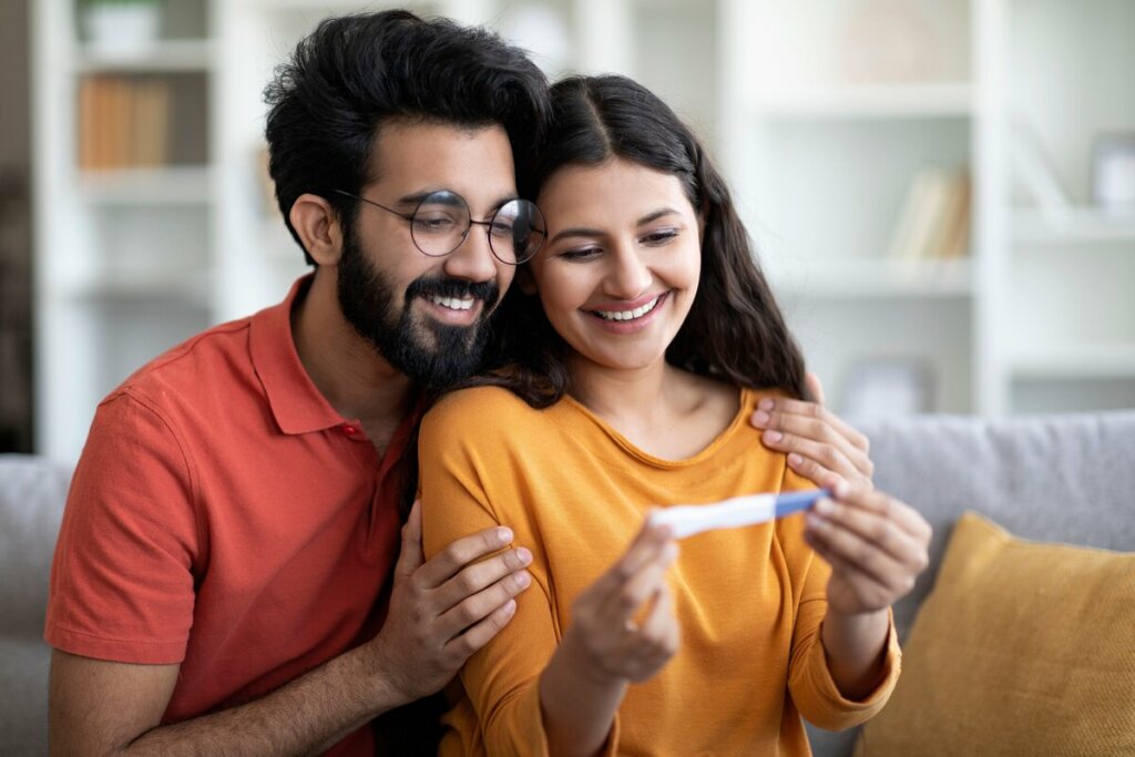 Homem é mulher sorrindo olhando oara um teste de gravidez