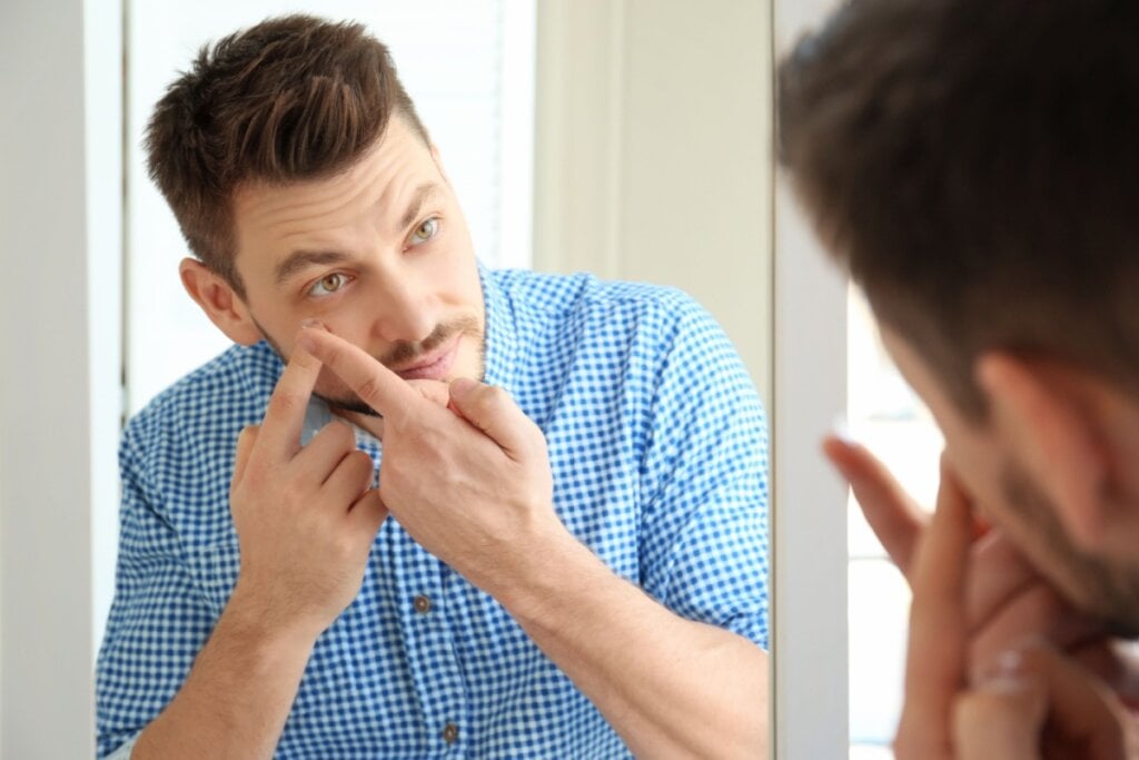 Homem colocando lente de contato olhando no espelho