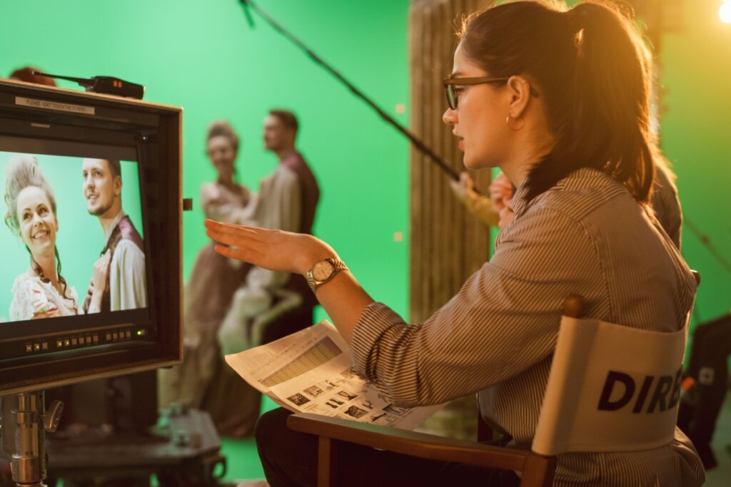 Mulher diretora de cinema sentada na cadeira olhando na tela vendo os atores.