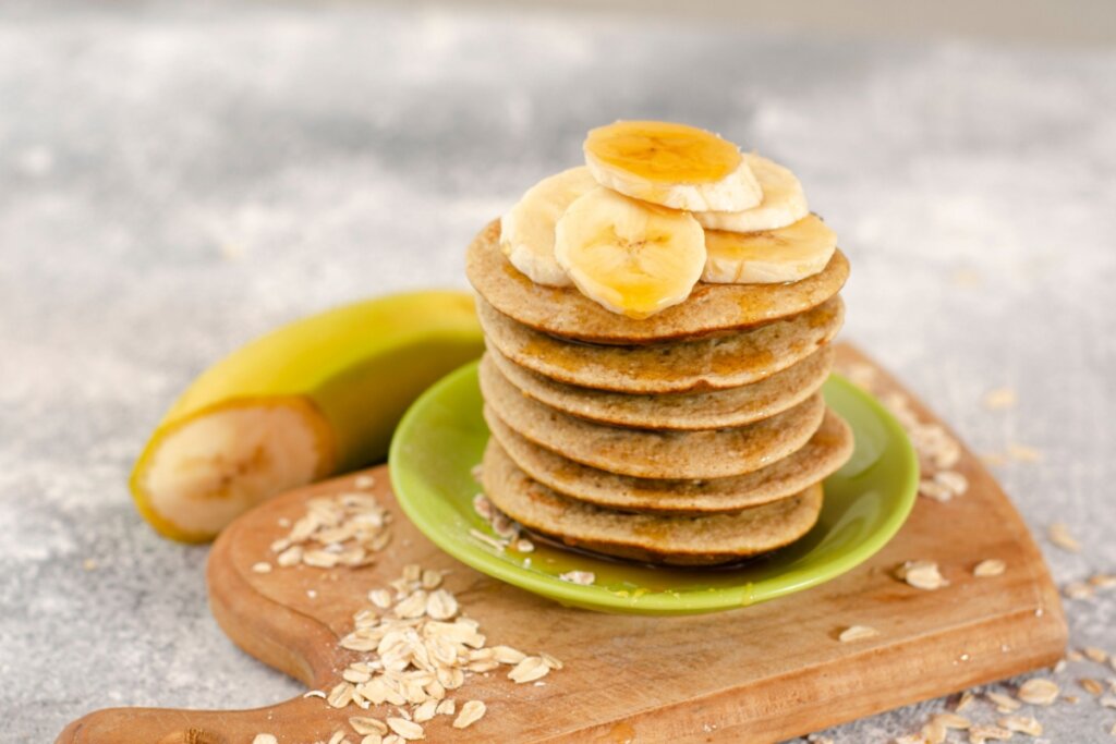 Panqueca de banana e aveia em um prato verde em cima de uma tábua de madeira