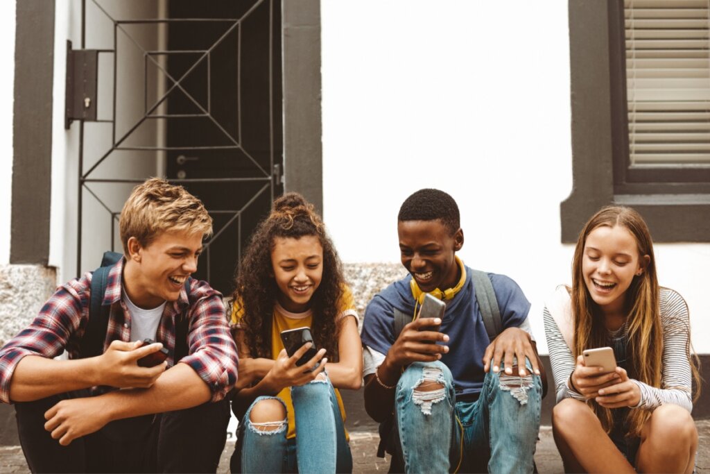 Quatro adolescentes rindo e olhando no celular