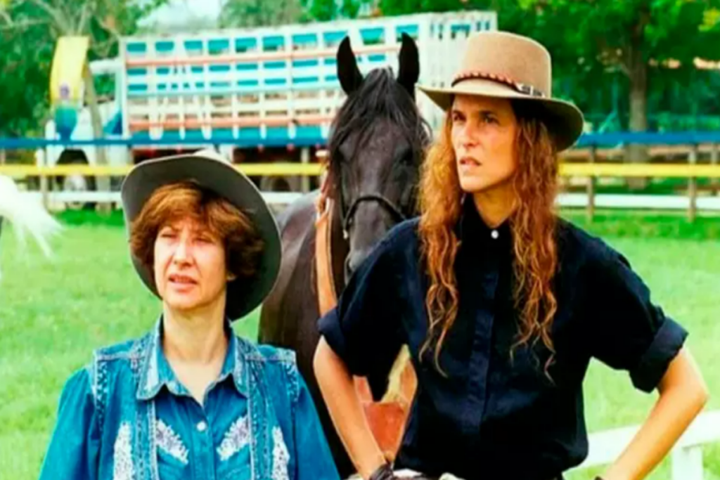 Duas mulheres uma ao lado da outra em um gramado com chapéus de cowboy 