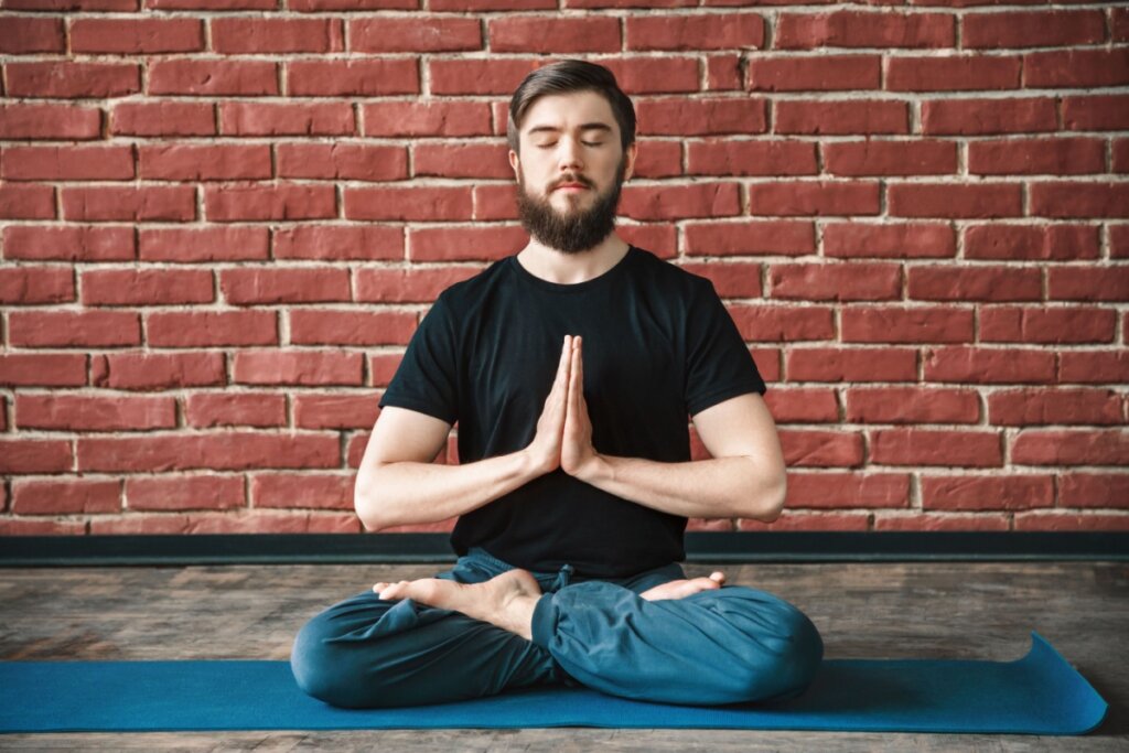 Homem sentado em postura de lótus meditando