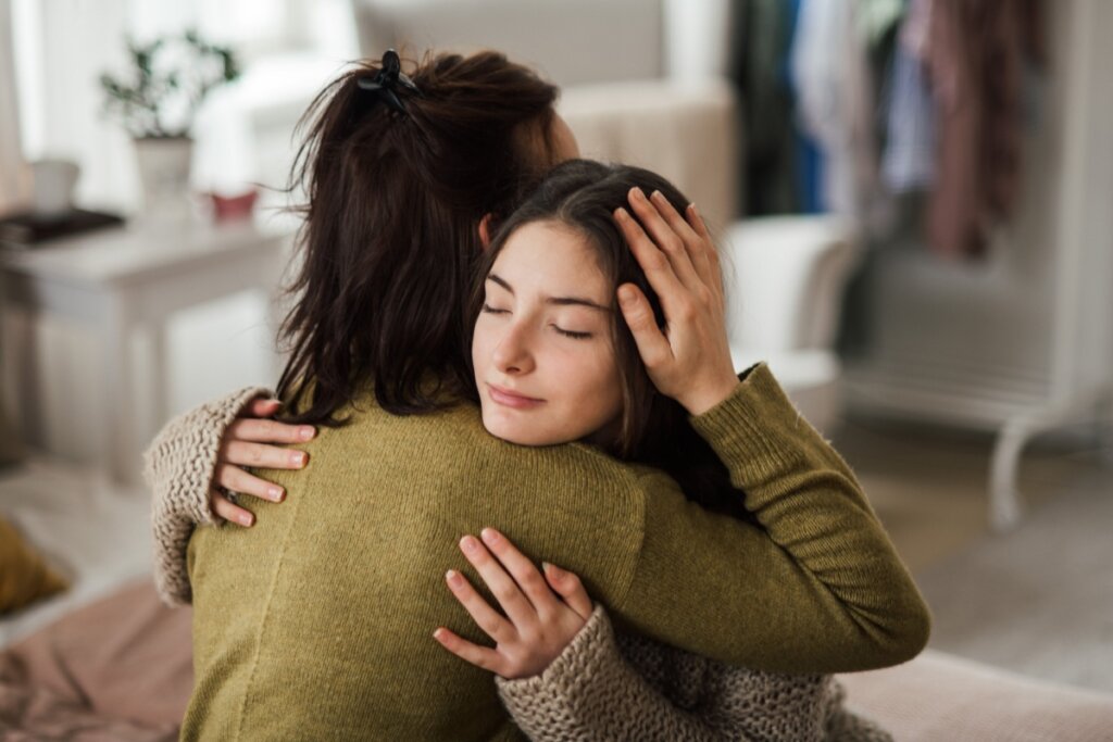 Mãe abraçando menina adolescente